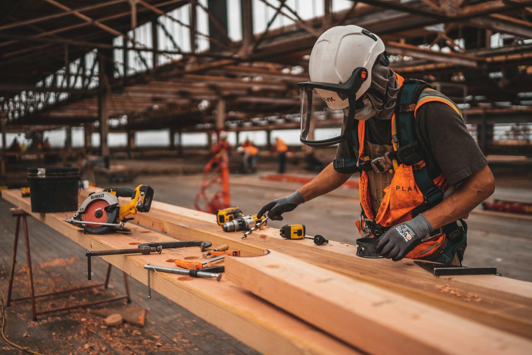 Tradesperson measuring and cutting timber on site